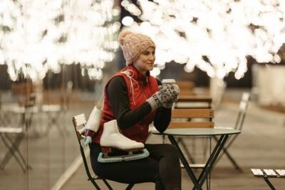 A woman holding a warm beverage near ice skating.