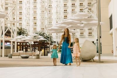 A mother holding her daughters hands at a resort.