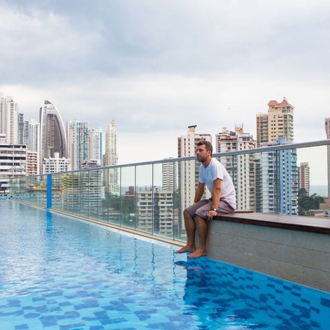 A person sitting on the edge of a rooftop pool