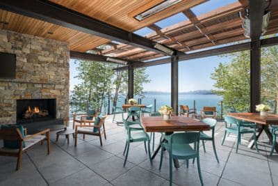 A rooftop deck with dining tables, a fireplace and a water view
