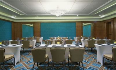 Medium-size meeting room with a classroom setup as well as wood paneling and blue upholstered wall coverings