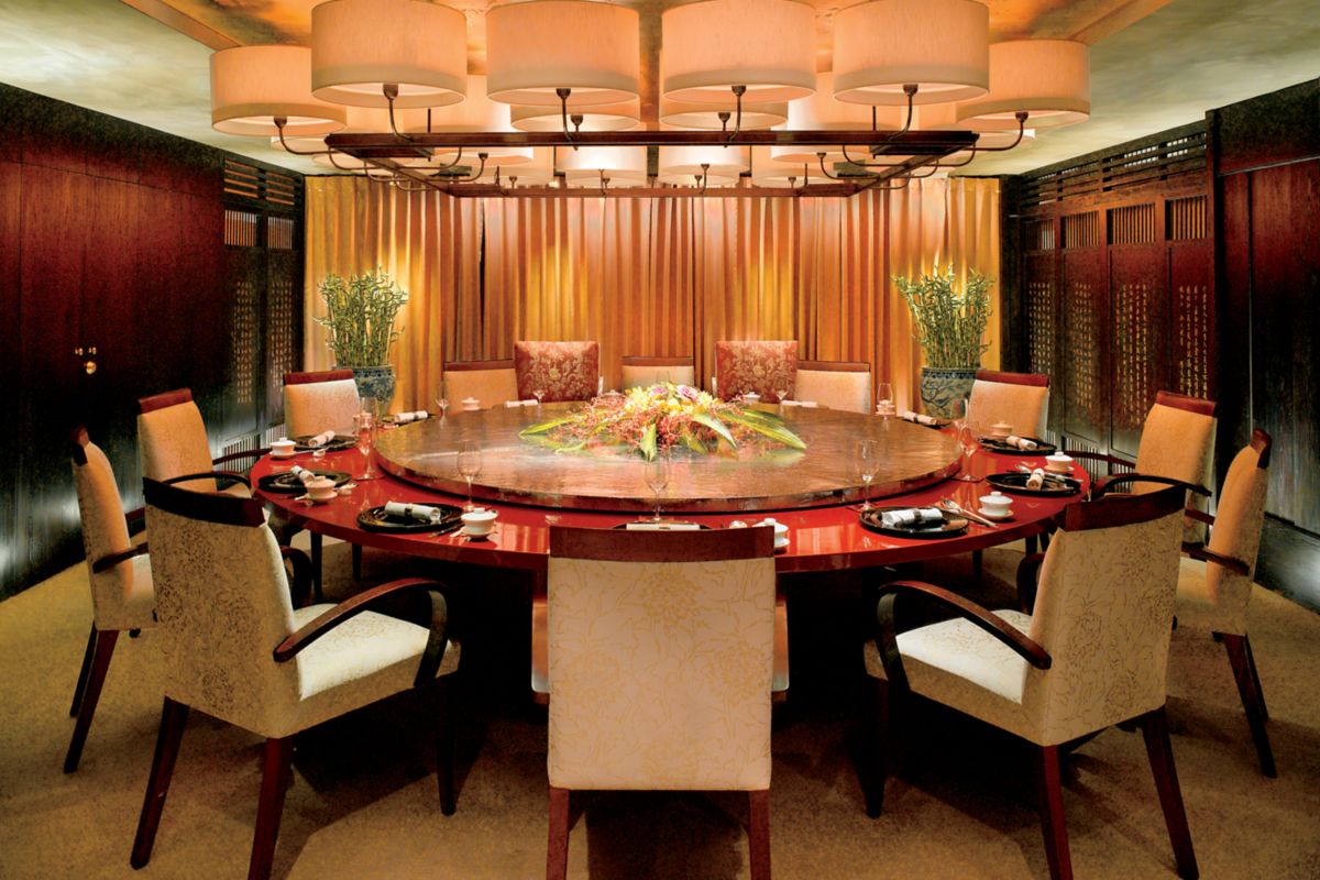 Roundtable in a private dining space with dark wood paneling on the sides, curtains at the back and a lamp-like light fixture