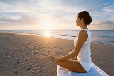 Woman sitting cross-legged in a meditative pose on the beach