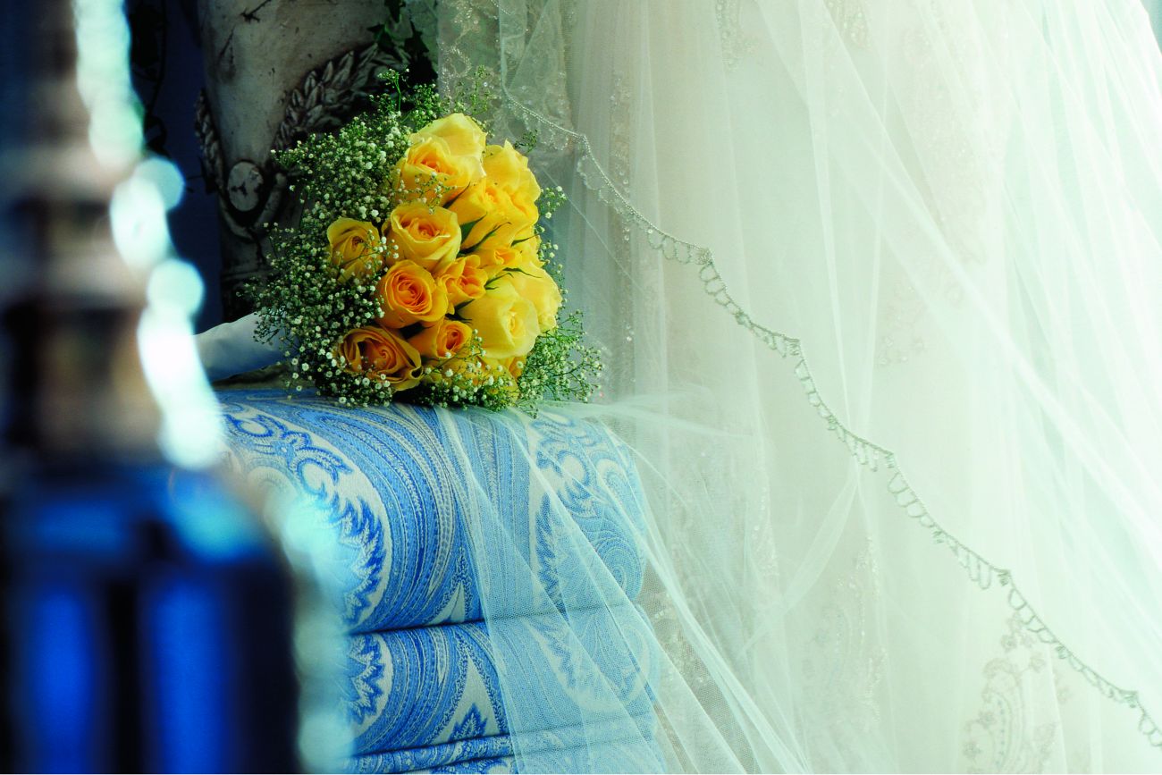 Mannequin draped in the lace and tulle of a wedding gown with a yellow bouquet nearby