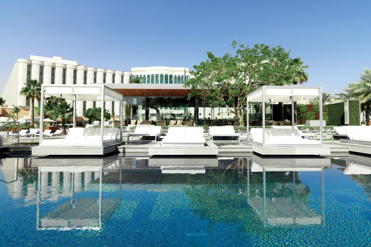A crystalline pool with private, bedlike lounges extending into the water as the resort towers in the background