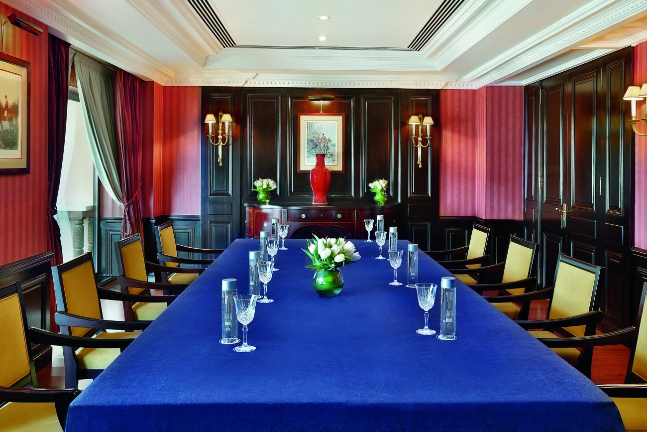 Meeting room with dark wood wainscoting, red wallpaper and a conference table draped in a royal blue cloth