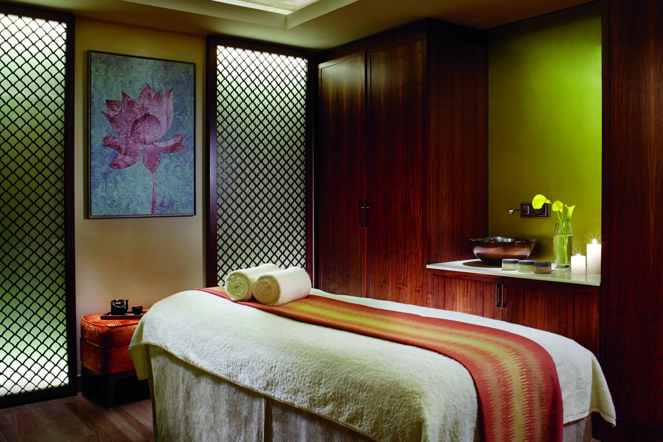 Room with a massage table, wooden cabinetry, a sink and carved-wood screens