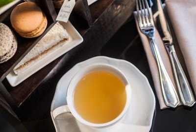 A cup of tea sits next to an assortment of sweet and savory snacks