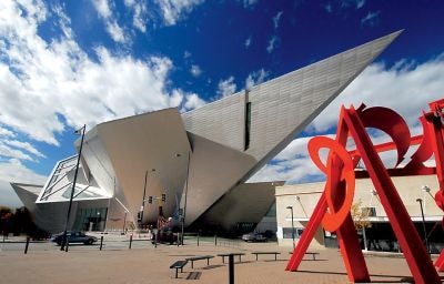 The contemporary, metallic exterior of the Denver Art Museum against a bright blue sky