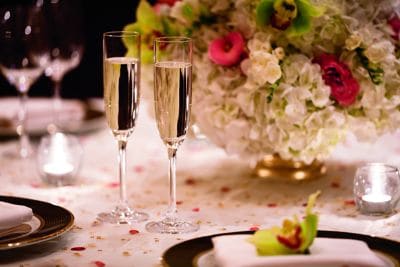 Two glasses of champagne on a petal-strewn table during a wedding reception