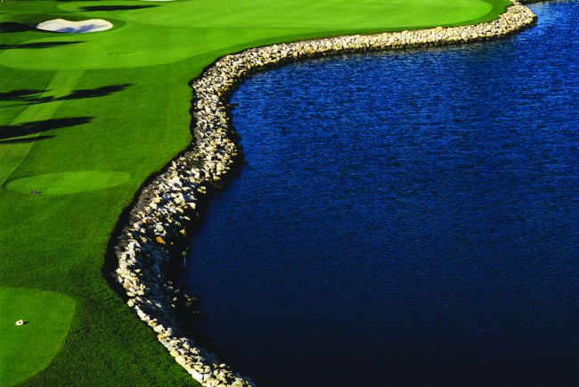 A body of water curves along a golf green