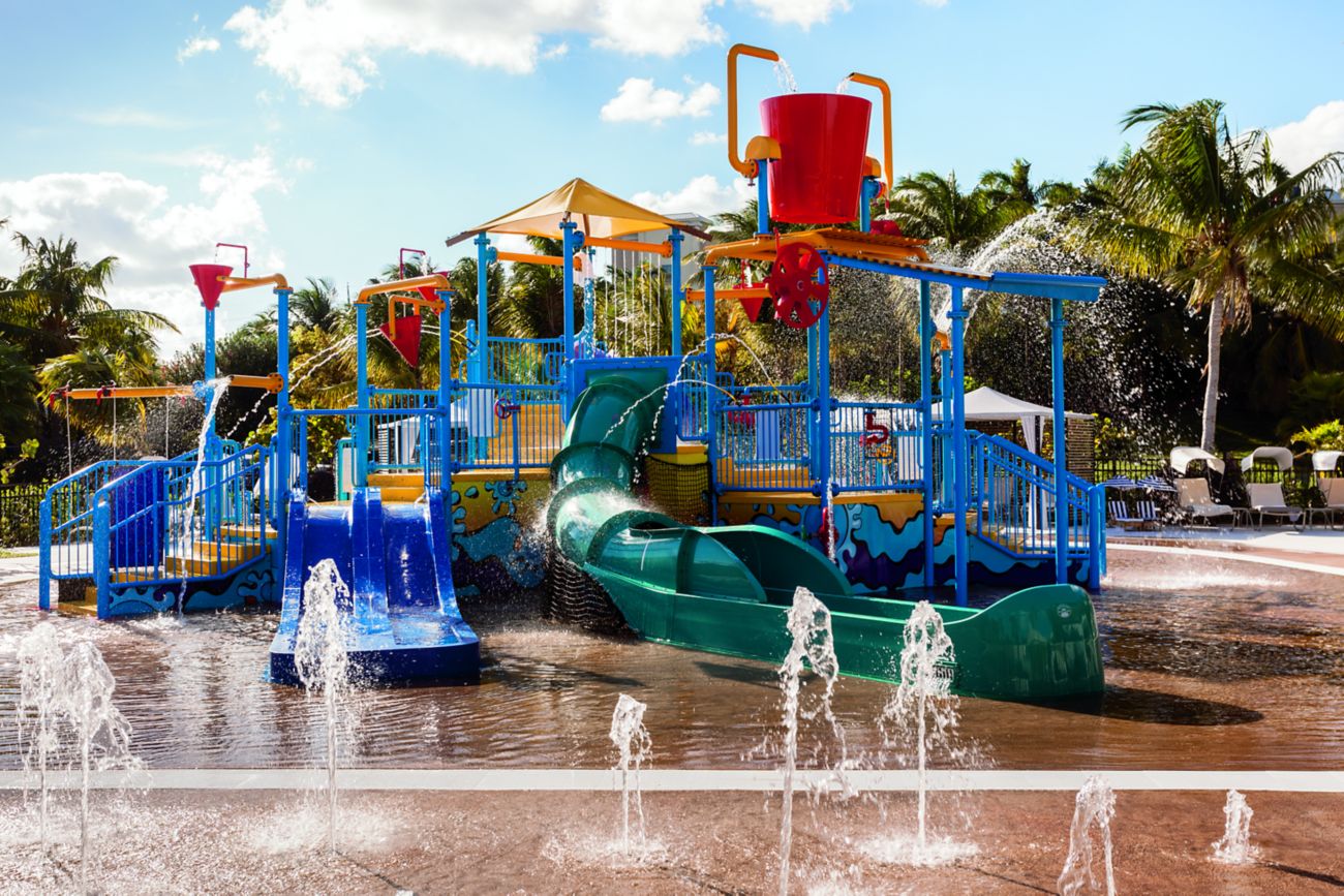 An outdoor playground with slides surrounded by shooting water jets
