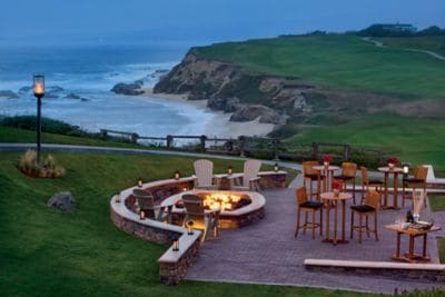 Terrace with cocktail tables and a firepit overlooking the ocean
