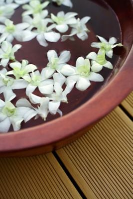 Angled view of copper bowl with white blossoms floating in water