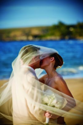 Newlyweds share a romantic kiss on the beach