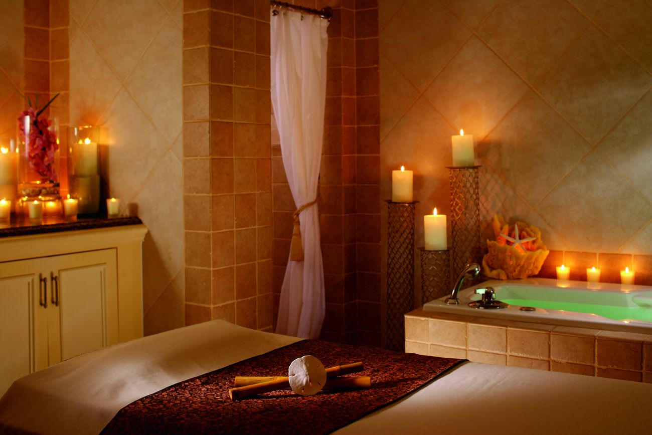 A candle-lit room with a massage table and a tub
