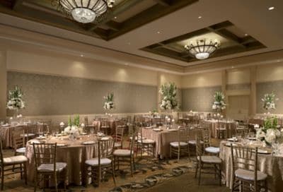Reception with roundtables, champagne-colored tablecloths and tall green-and-white floral centerpieces