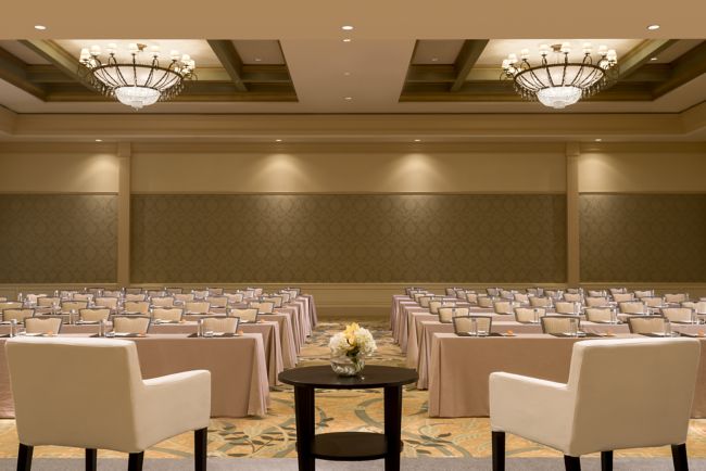 Classroom setup in a cream-colored ballroom with two contemporary white chairs on a dais