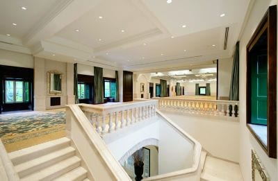 Wide view of a staircase leading to a carpeted foyer with windows