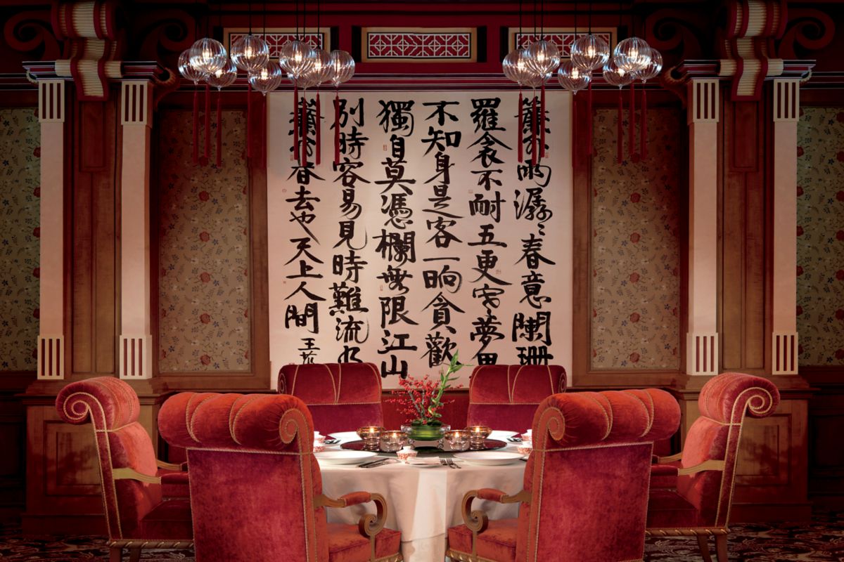 A table with six plush chairs in front of a large scroll with script