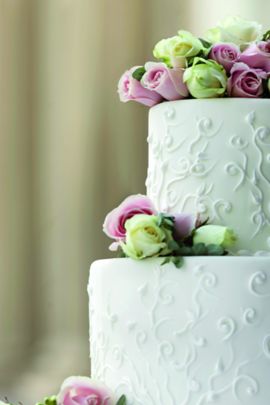 Two-tier wedding cake garnished with white and lavender roses