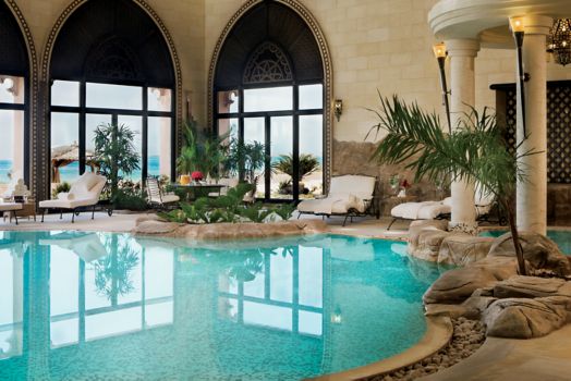 Indoor pool with arched windows and a Jacuzzi under a pillared dome