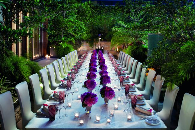 Garden with a long dining table with vases of flowers down the middle