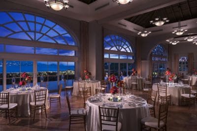 Formal banquet setup in a room with large windows overlooking a night sky