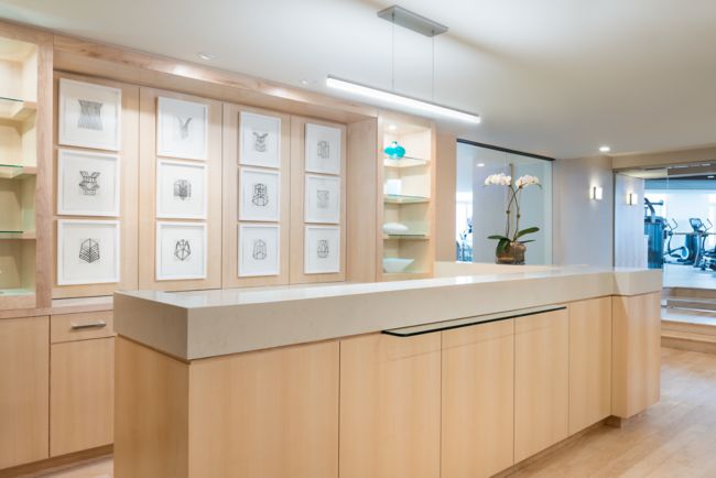 A space with light-wood flooring, shelving and a long counter