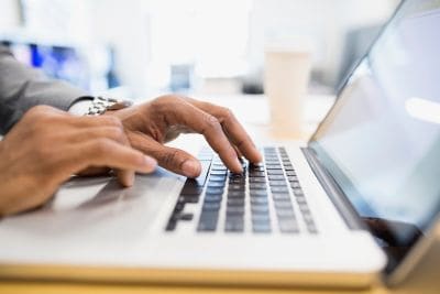 手提电脑特写，双手放在键盘上。