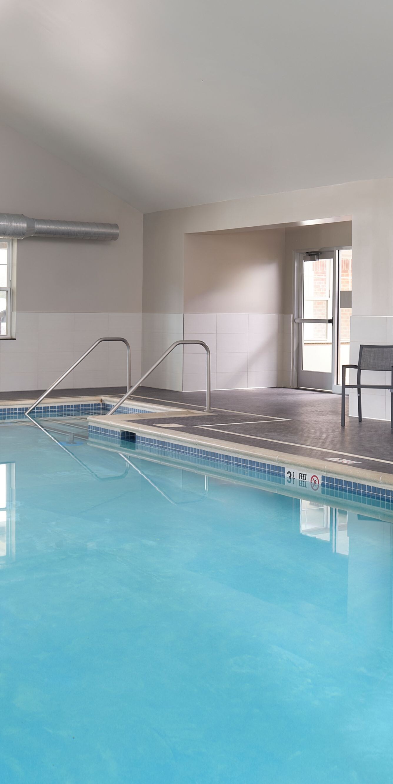Indoor pool with lounge chairs and windows