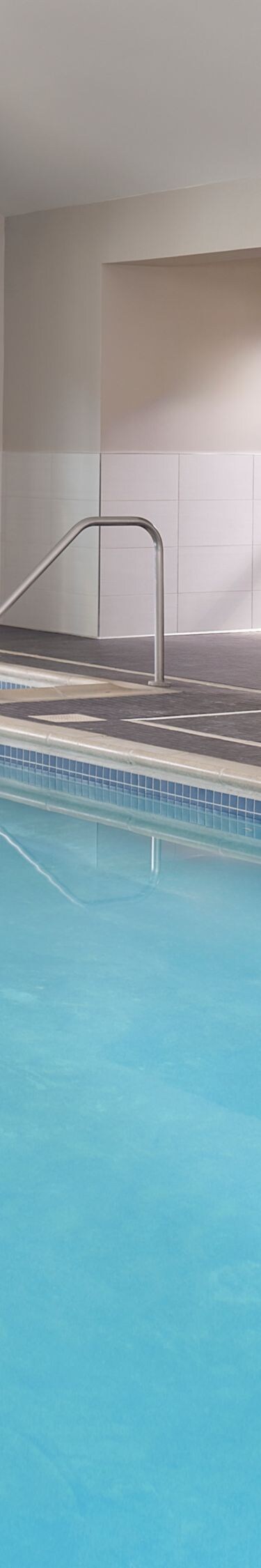 Indoor pool with lounge chairs and windows
