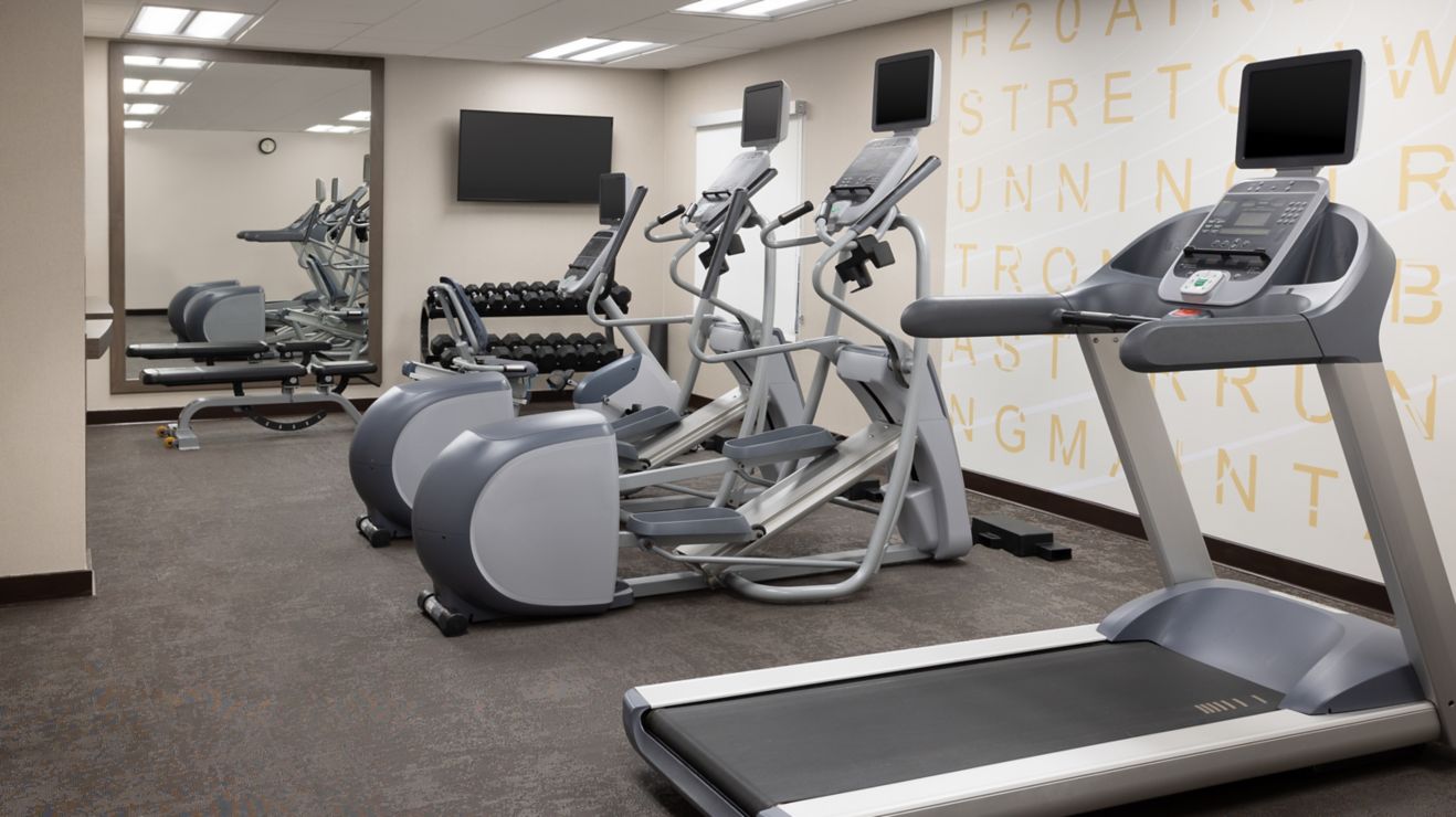 Fitness room with cardio machines, weights.