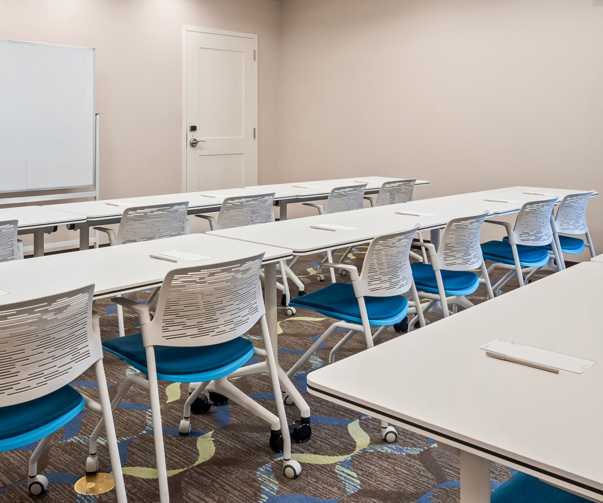 Meeting room with tables, chairs, and whiteboard