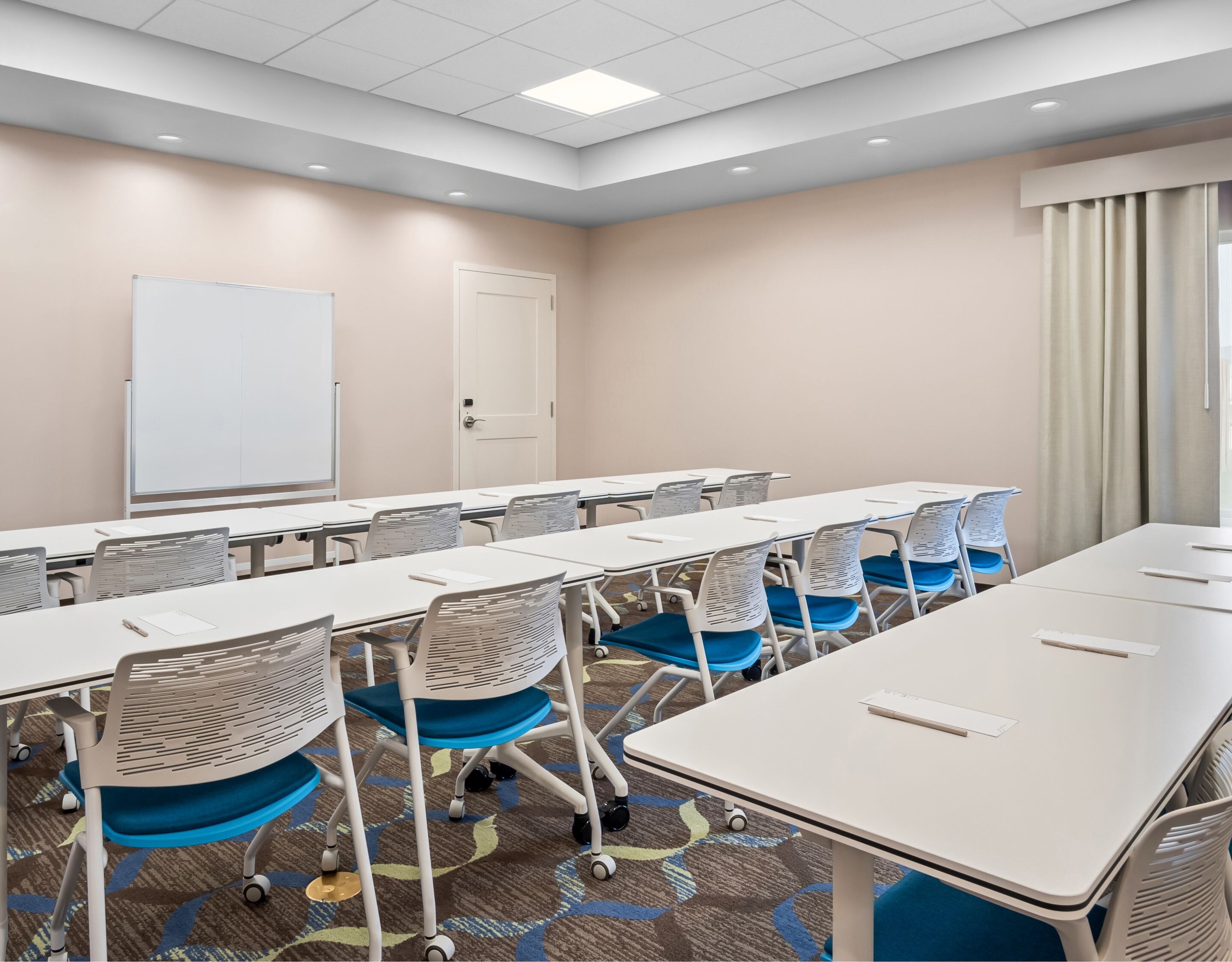 Meeting room with tables, chairs, and whiteboard