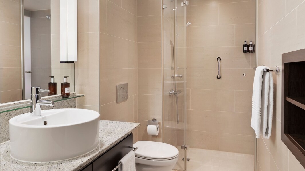 Ванная комната с унитазом, раковиной, полотенцами и безбарьерным душем