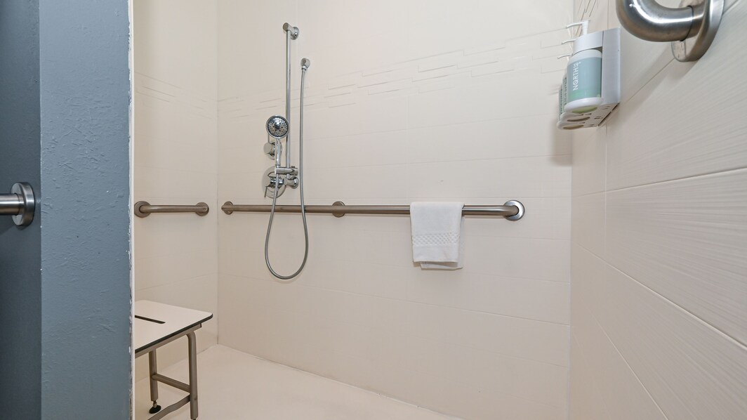 Roll in shower with grab bars and chair.