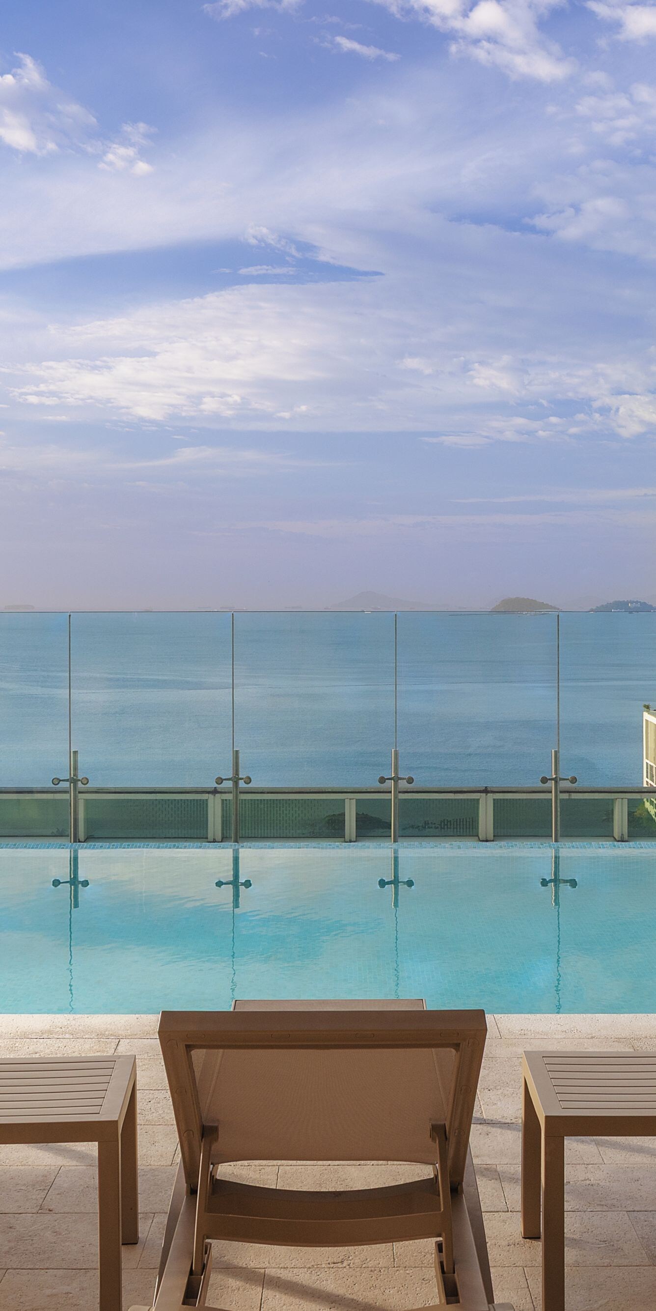 Sillas reclinables junto a la piscina con vista al agua