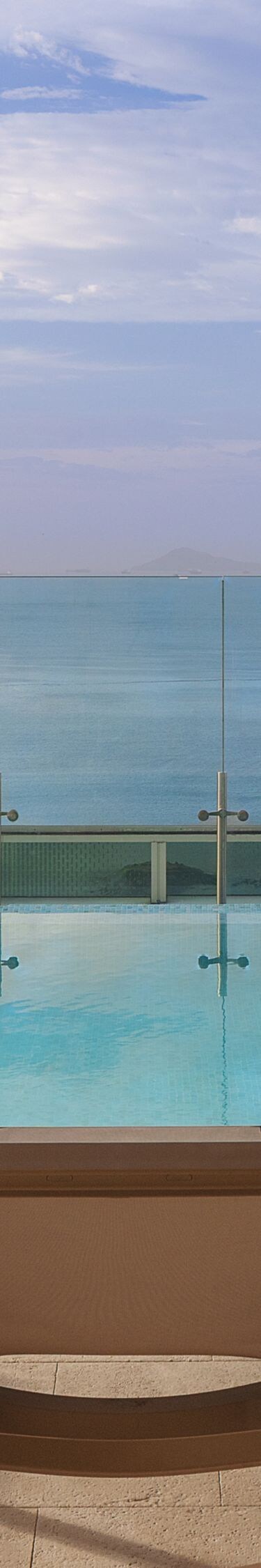 Sillas reclinables junto a la piscina con vista al agua
