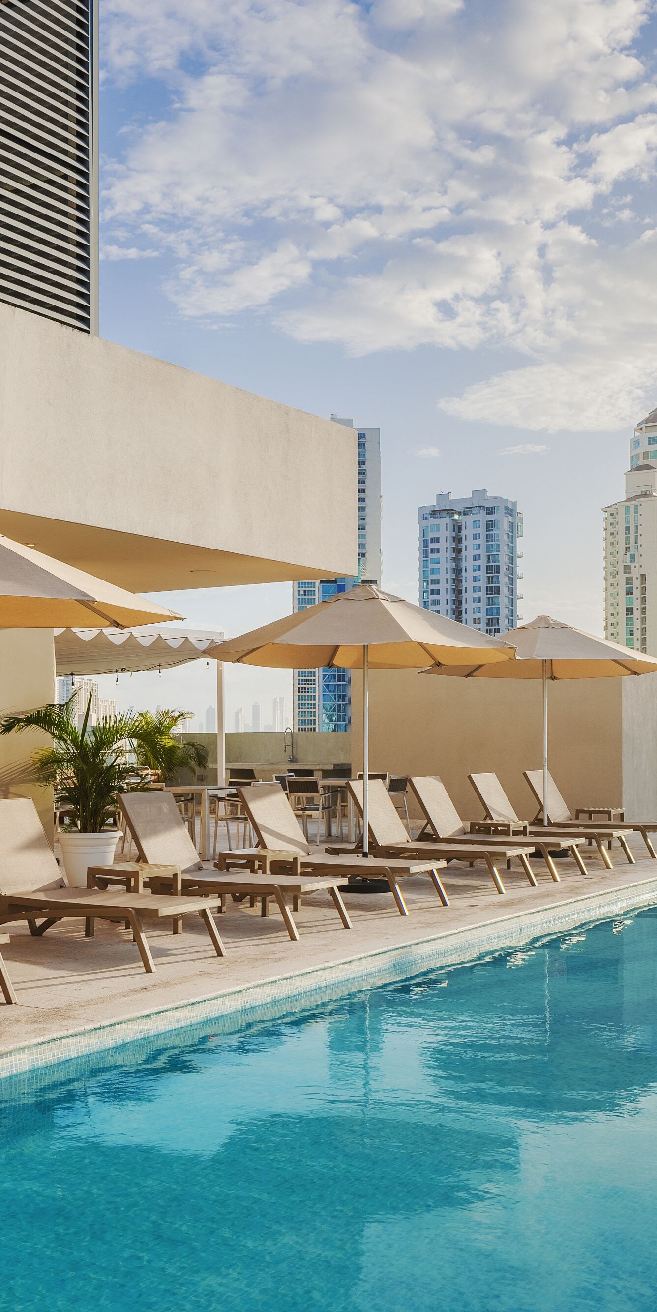 Sillas reclinables junto a la piscina con vista a la ciudad