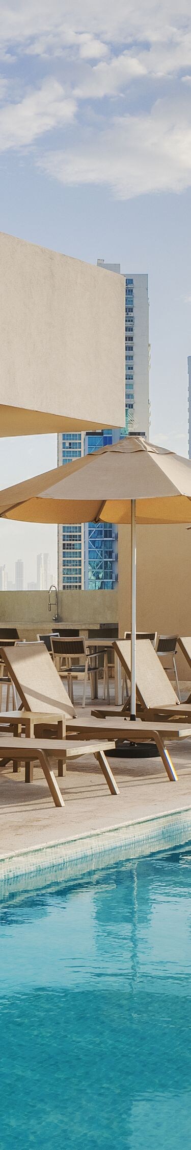 Sillas reclinables junto a la piscina con vista a la ciudad
