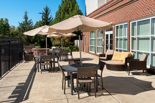 outdoor seating, tables, umbrellas, firepit, trees