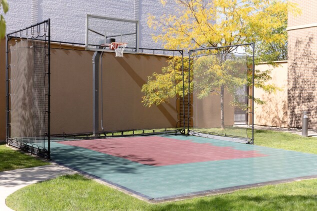 An outdoor sport court with basketball hoop.