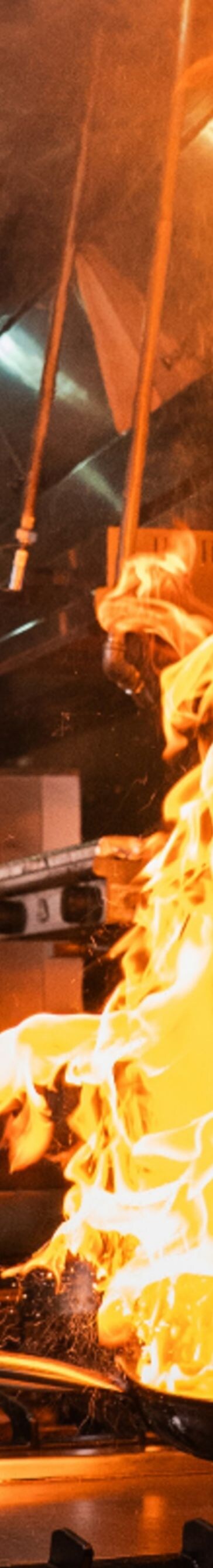 A chef cooking meat over an open flame grill.