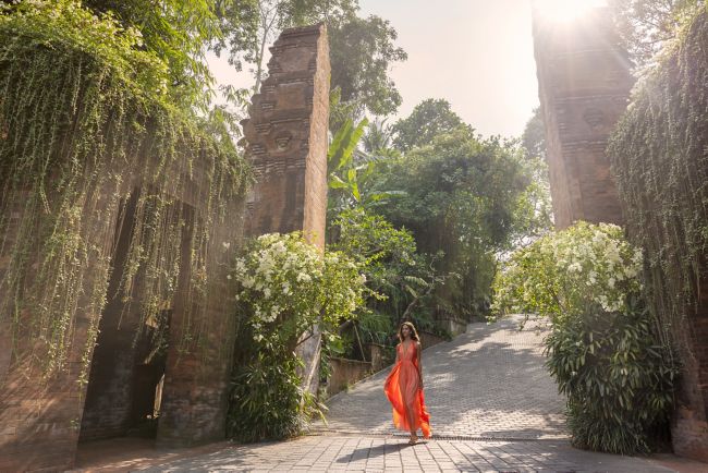 woman in orange, walking through stone gate