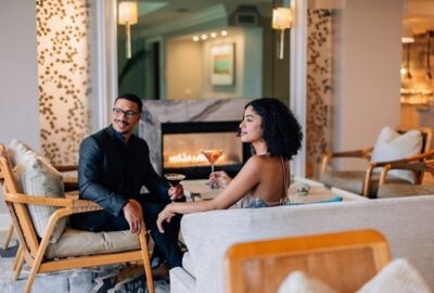 Couple enjoying cocktails by the fireplace. 