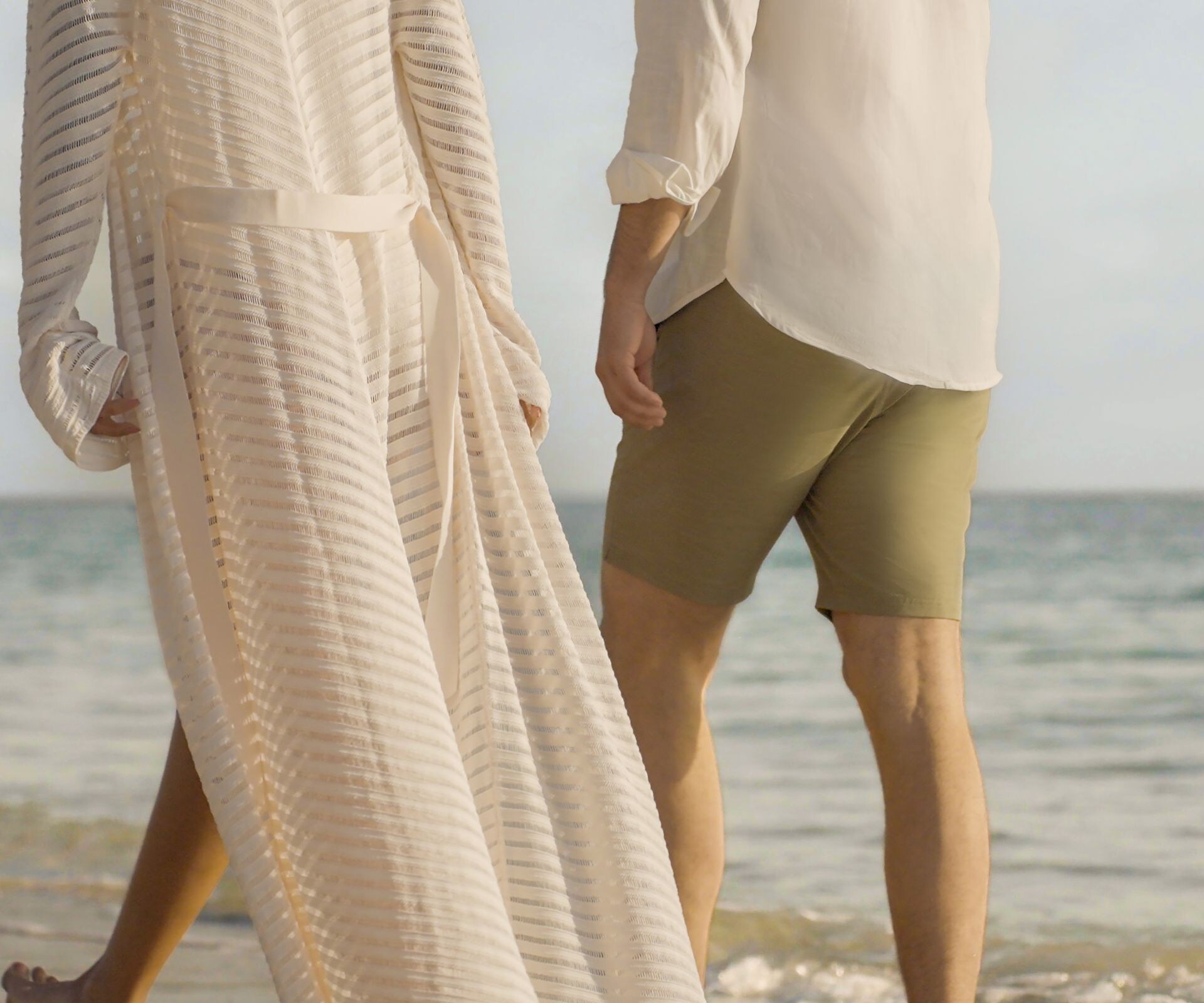 Two people walking beside the ocean shoreline