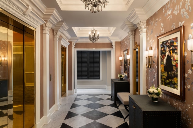 A hallway in a hotel with brass elevator door and 