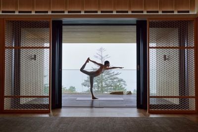 Woman doing yoga by a window overlooking a lake