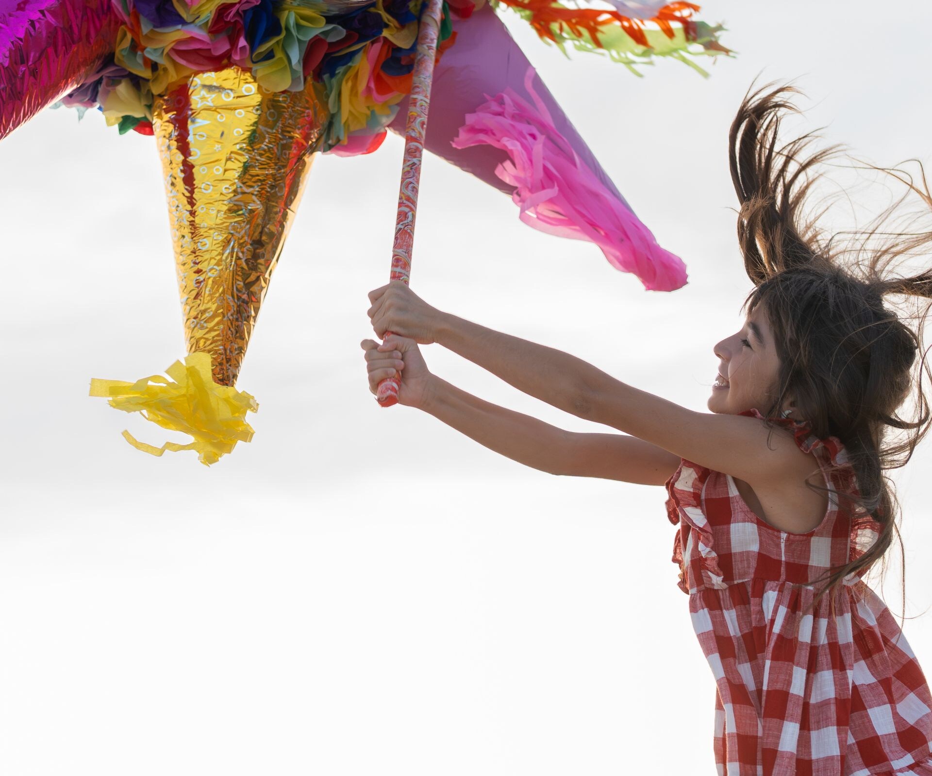 A child breaking a colorful pinata at sunset